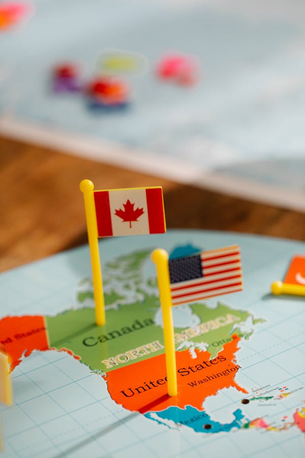 Photo by Lara Jameson Close-up of miniature Canada and USA flags on a world map depicting North America, symbolizing travel and education.