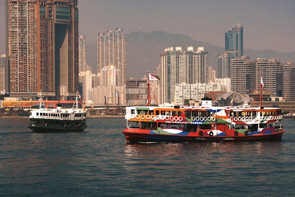 Photo by Harry Shum A vibrant ferry sails through Victoria Harbour with Hong Kong skyscrapers in the background.