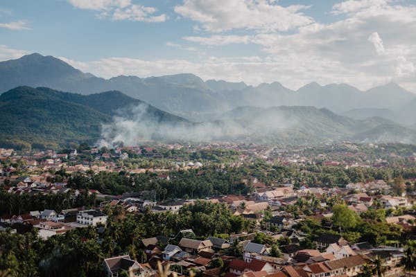Photo by ROMAN ODINTSOV Drone view of picturesque valley with village located near mountain range against blue sky with fluffy clouds on sunny summer day