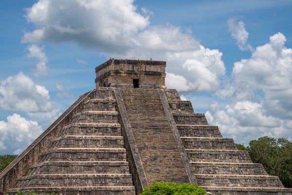 Photo by Ollie Craig Stunning view of El Castillo pyramid at Chichén Itzá under a bright blue sky.
